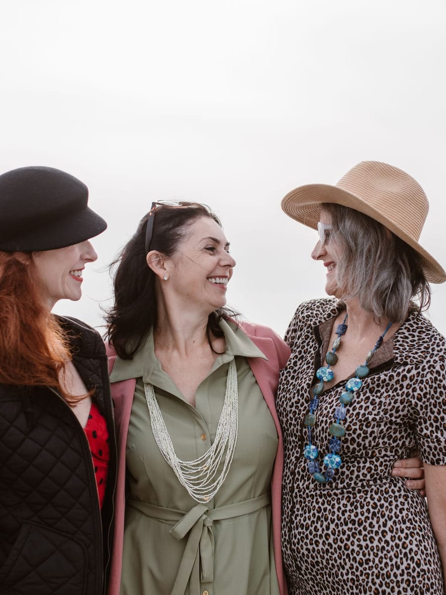 Tres mujeres riéndose juntas frente al mar