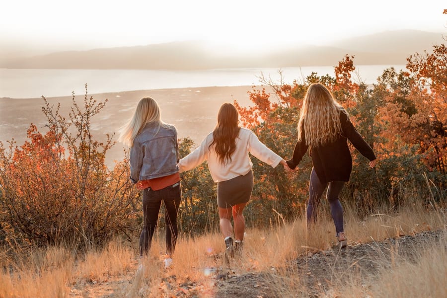 Tres mujeres caminando de la mano hacia el atardecer