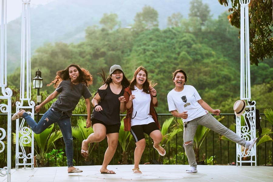 Cuatro mujeres saltando y riéndose en un mirador