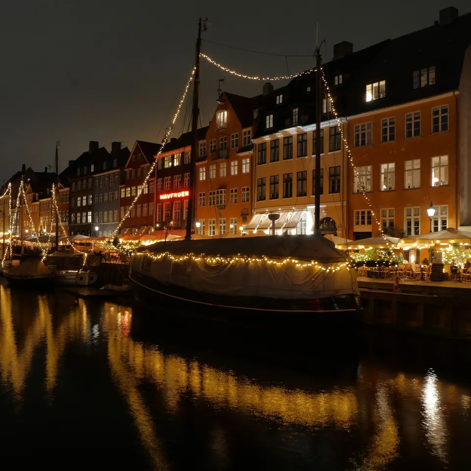 Canal de Nyhavn en Copenhague de noche, con barcos y casas iluminadas