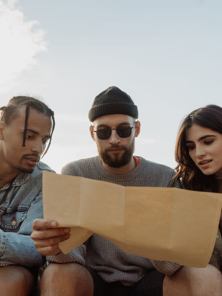 Tres amigos sentados en un banco mirando un mapa