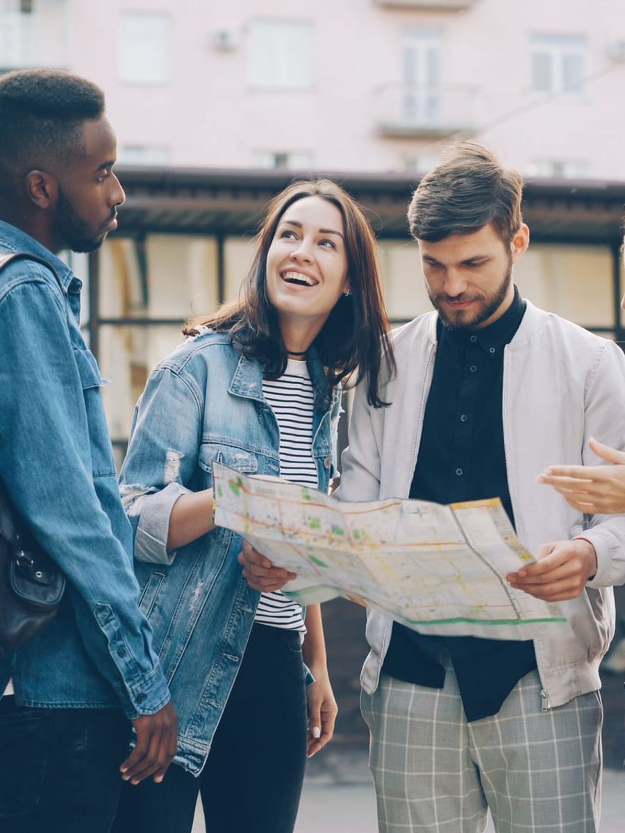 Cuatro amigos consultando un mapa en una calle de la ciudad